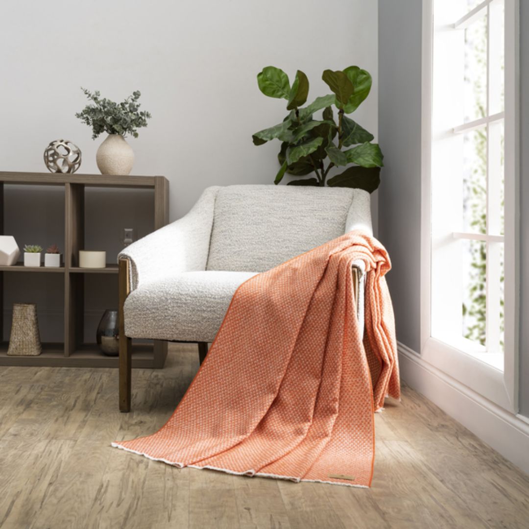 Cozy living room with a gray armchair draped with a Lands Downunder Hudson Valley Throw in Mandarin color