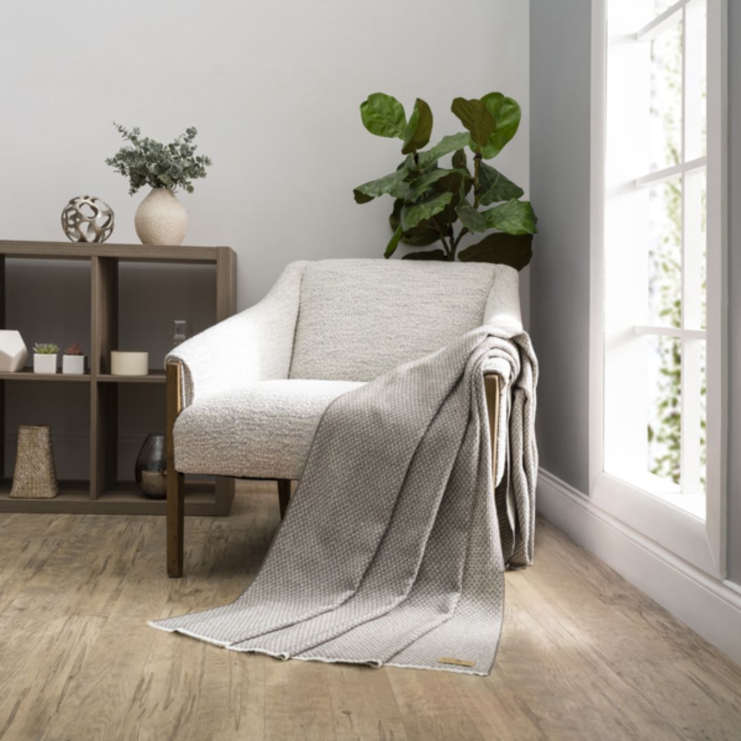 Cozy living room with a gray armchair draped with a Lands Downunder Hudson Valley Throw in Mink color