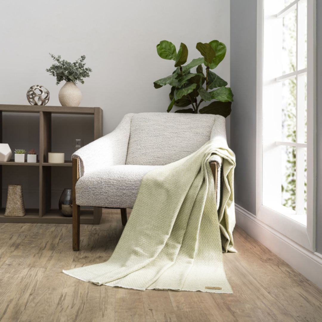 Cozy living room with a gray armchair draped with a Lands Downunder Hudson Valley Throw in White Sage color