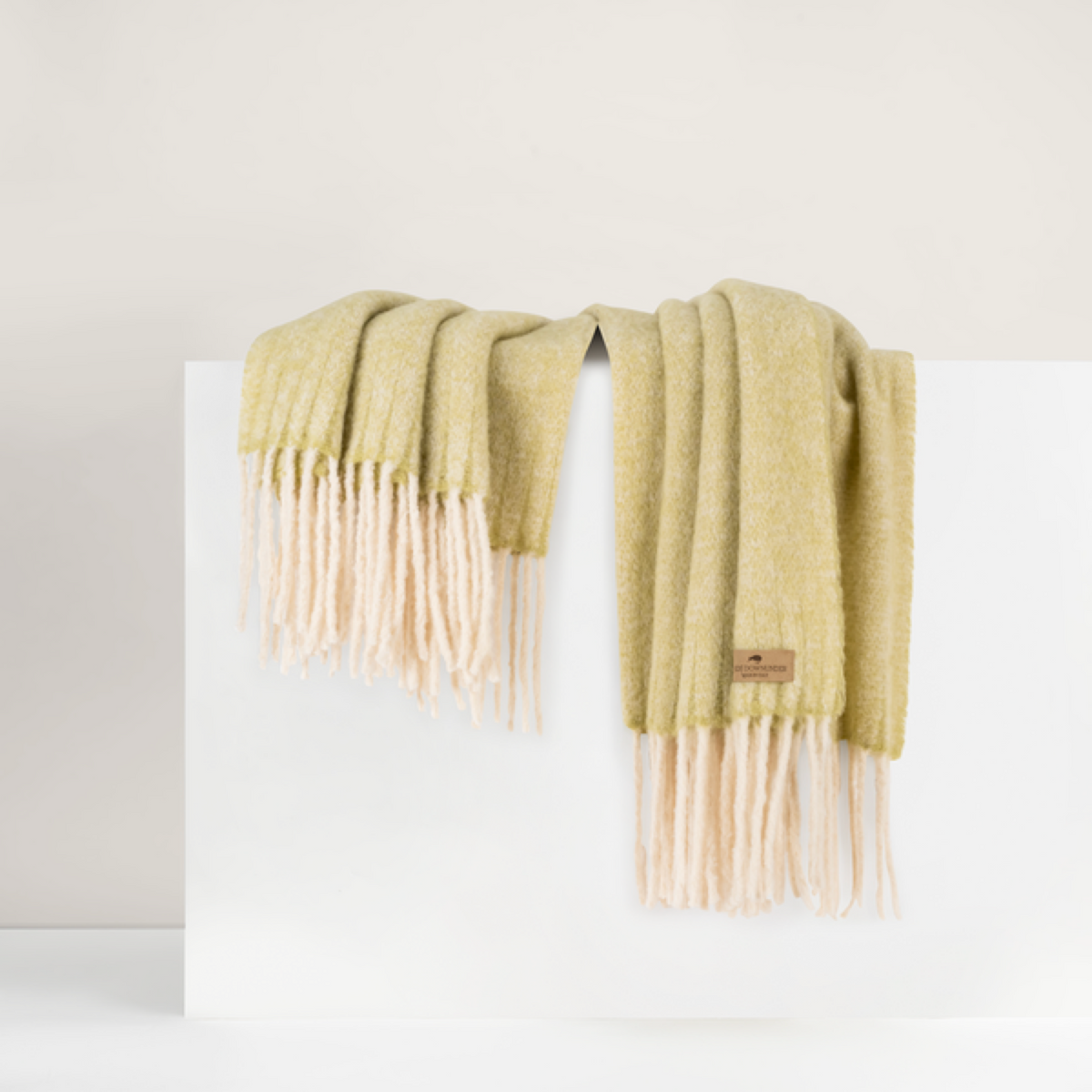 Lands Downunder Andes Throw, in Lemongrass color with fringe, is draped over a white surface