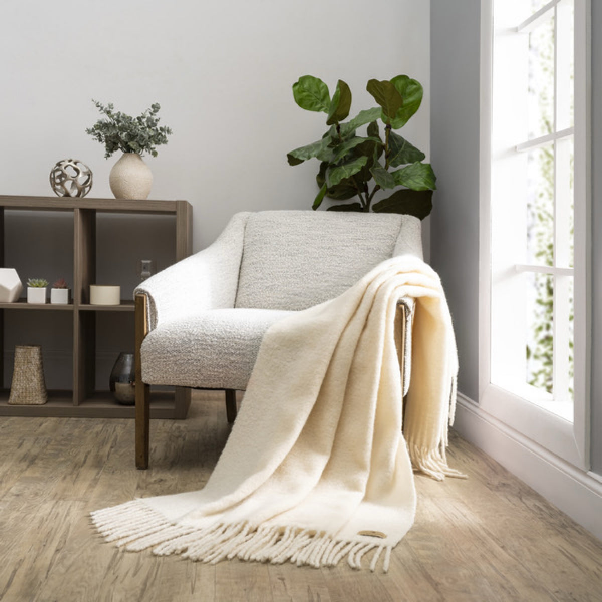 A Lands Downunder Andes Throw in Cream color draped over a light armchair by a window adds cozy home decor