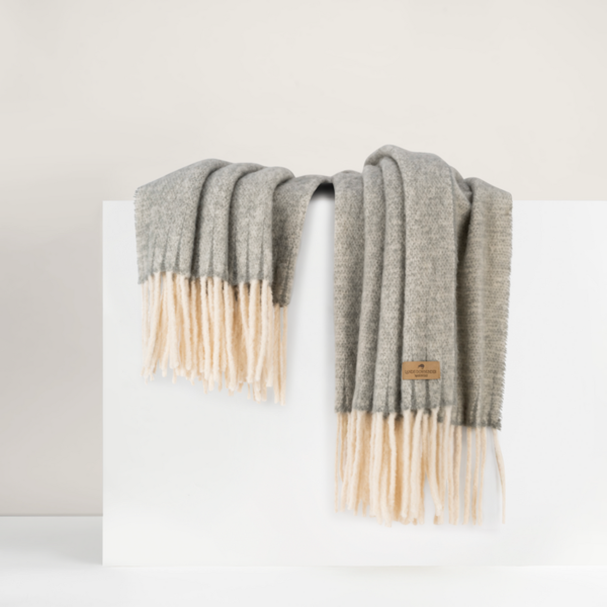 Lands Downunder Andes Throw, in Sterling color with fringe, is draped over a white surface