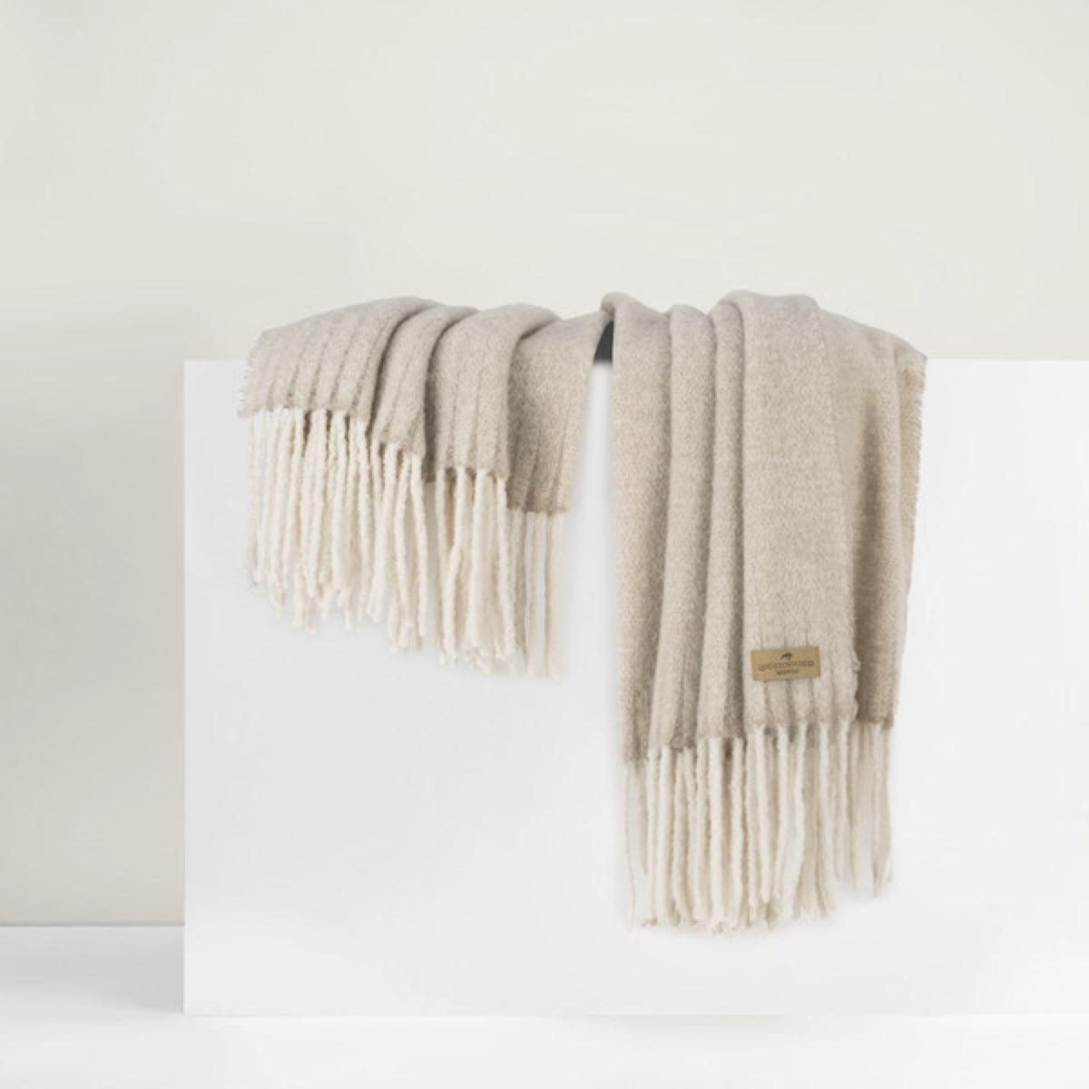 Lands Downunder Andes Throw, in Truffle color with fringe, is draped over a white surface