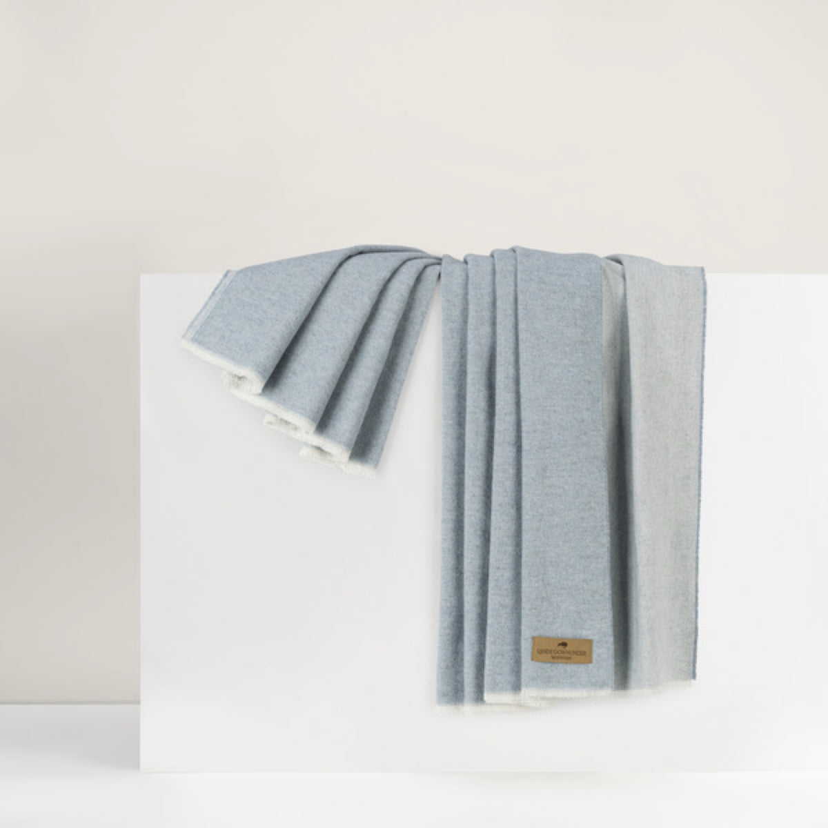 A Lands Downunder Aspen Peaks Throw in Crystal Blue color is draped over a white surface