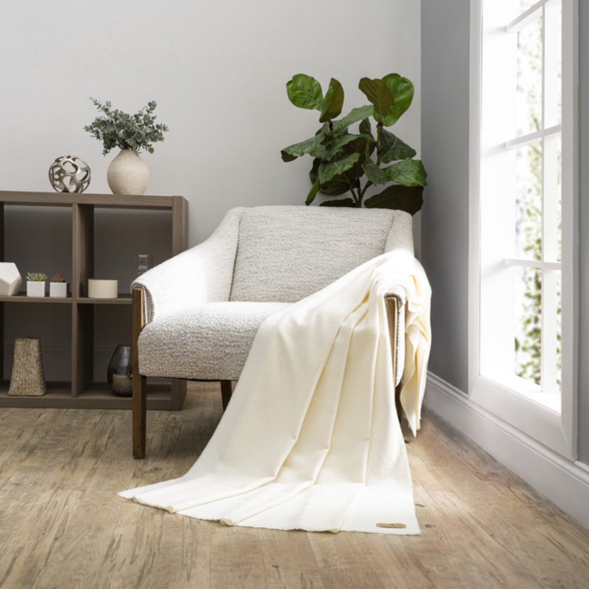 A Snow Lands Downunder Aspen Peaks Throw is draped over a cream armchair in a modern, minimalist living room
