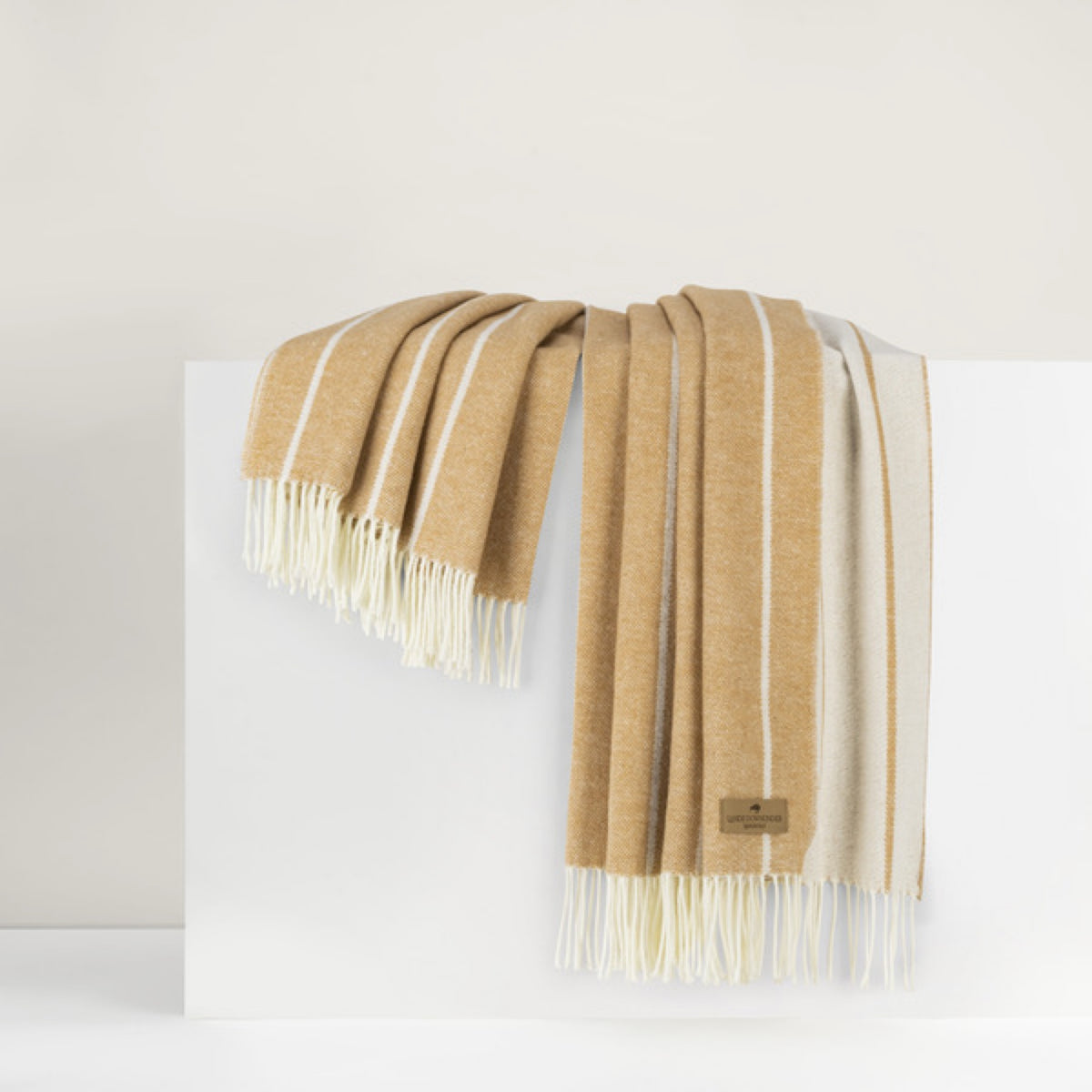 Biscotti Lands Downunder Fiji Stripe Throw with fringe, draped over a white surface