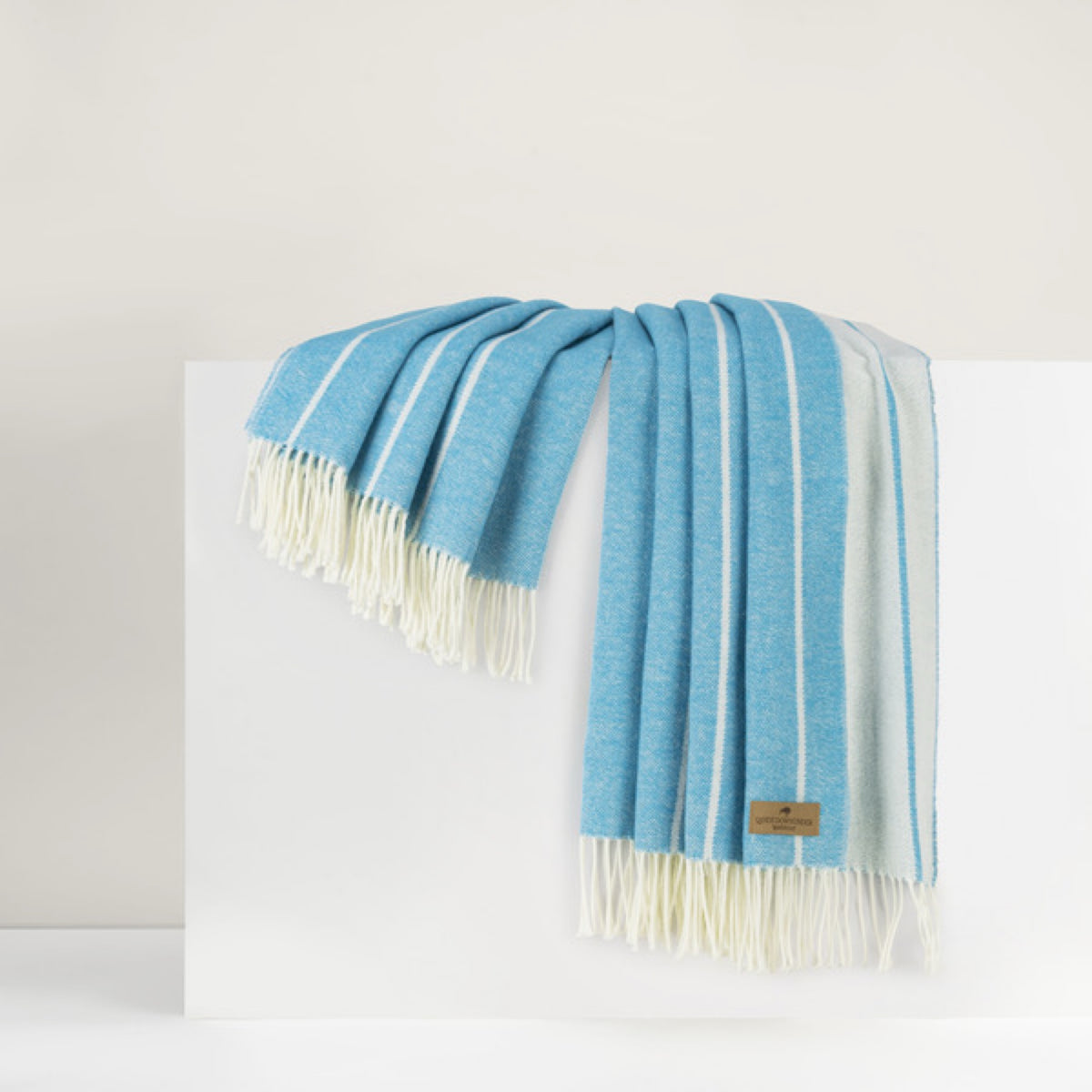 Island Blue Lands Downunder Fiji Stripe Throw with fringe, draped over a white surface