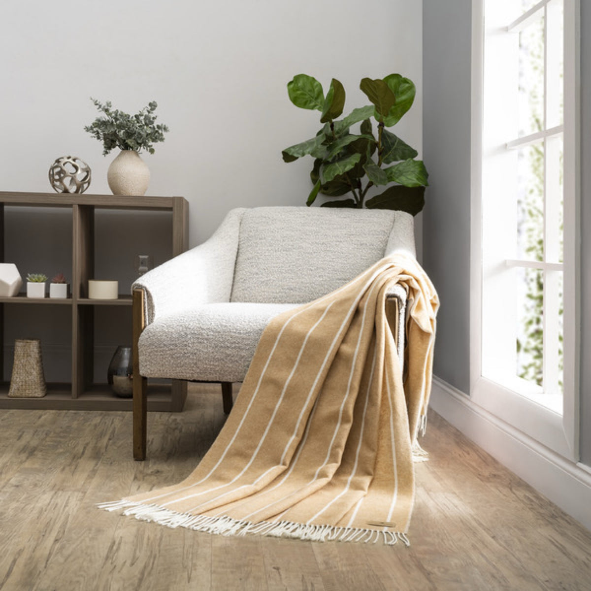 A white armchair with a Biscotti Lands Downunder Fiji Stripe Throw