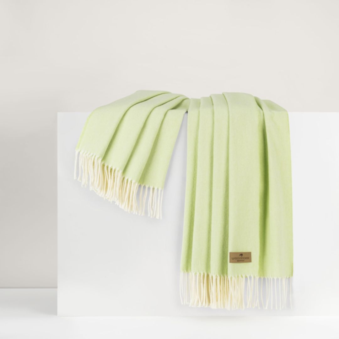 Light green throw with white fringe on a white background