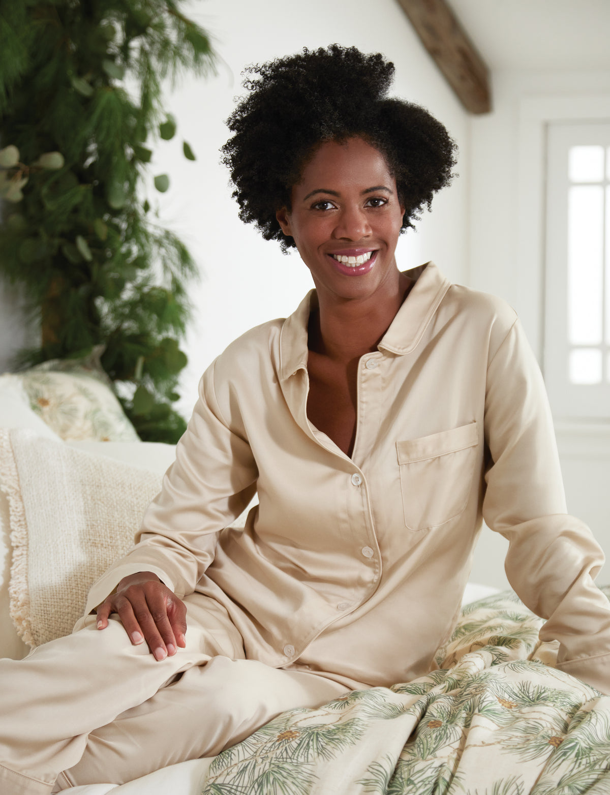 Woman Sitting on a Bed Wearing Pine Cone Hill Silken Solid Pajama in Sand Color