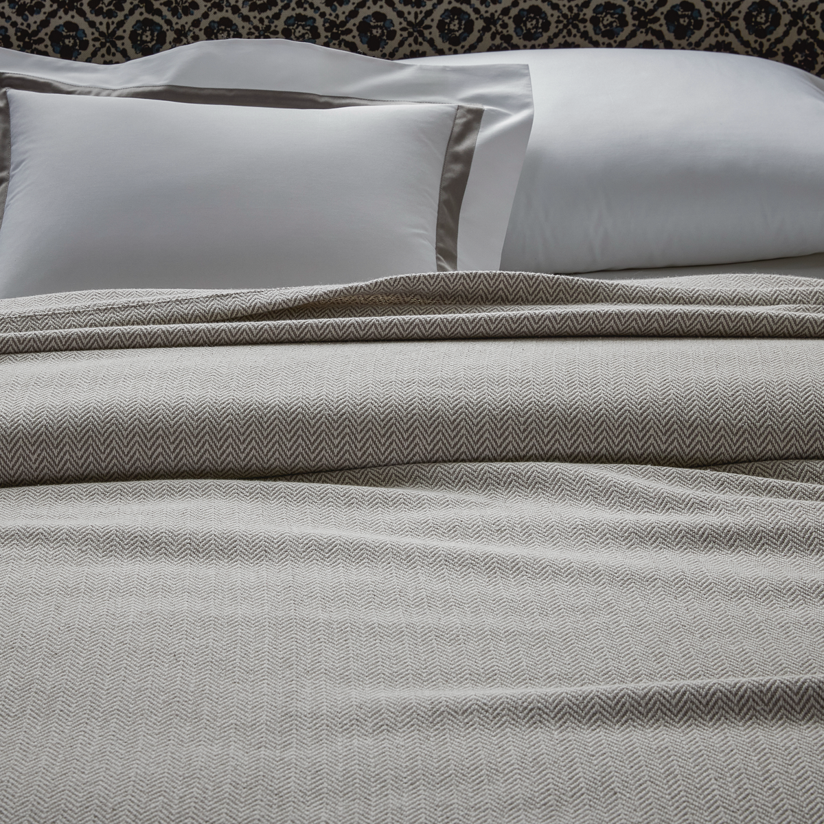 Closeup of Matouk Avalon Blanket in Platinum color with Lowell Platinum Sham
