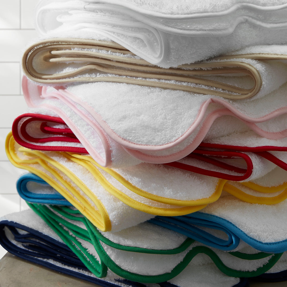 Stack of Matouk Cairo Scallop Bath Towels and Mats in Different Colors