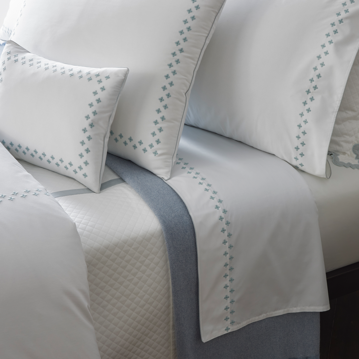 White Egyptian cotton percale bedding set with blue cross trim, quilted cover, and Matouk Casablanca bedding blanket.