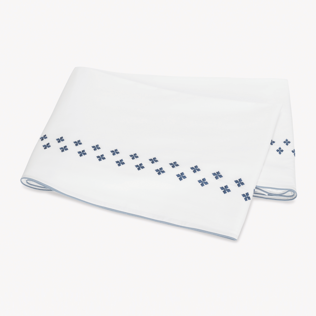 Folded white Flat Sheet in Egyptian cotton percale with Matouk Casablanca Embroidery in Indigo color