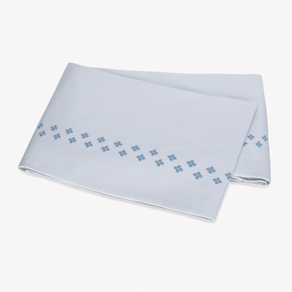 Folded white Flat Sheet in Egyptian cotton percale with Matouk Casablanca Embroidery in Sky Blue color