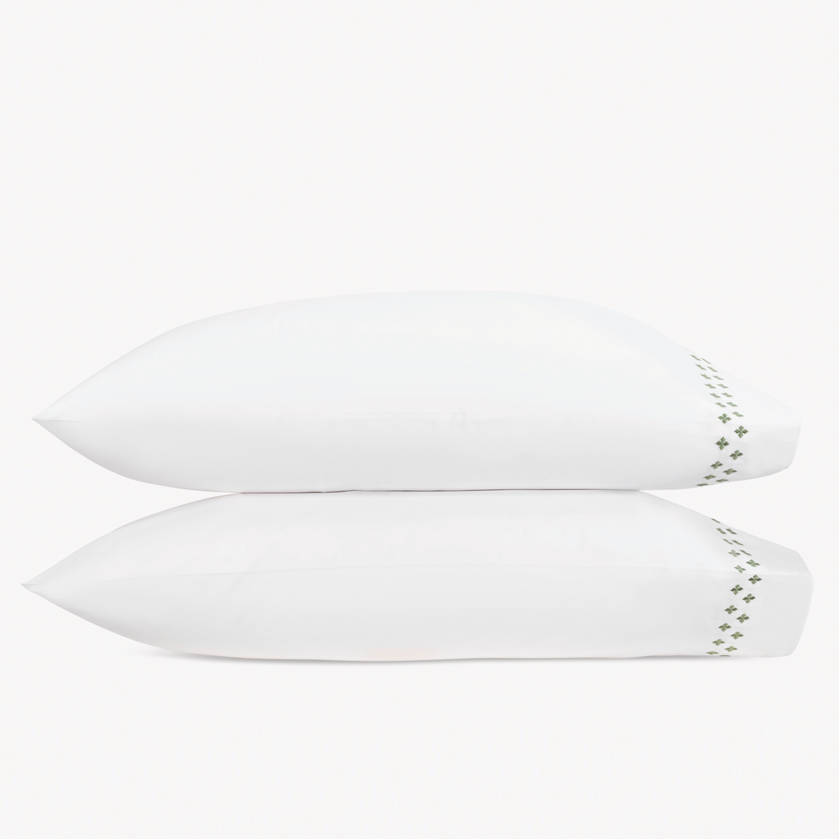Two white pillows stacked horizontally feature Matouk Casablanca Embroidery in Clover color