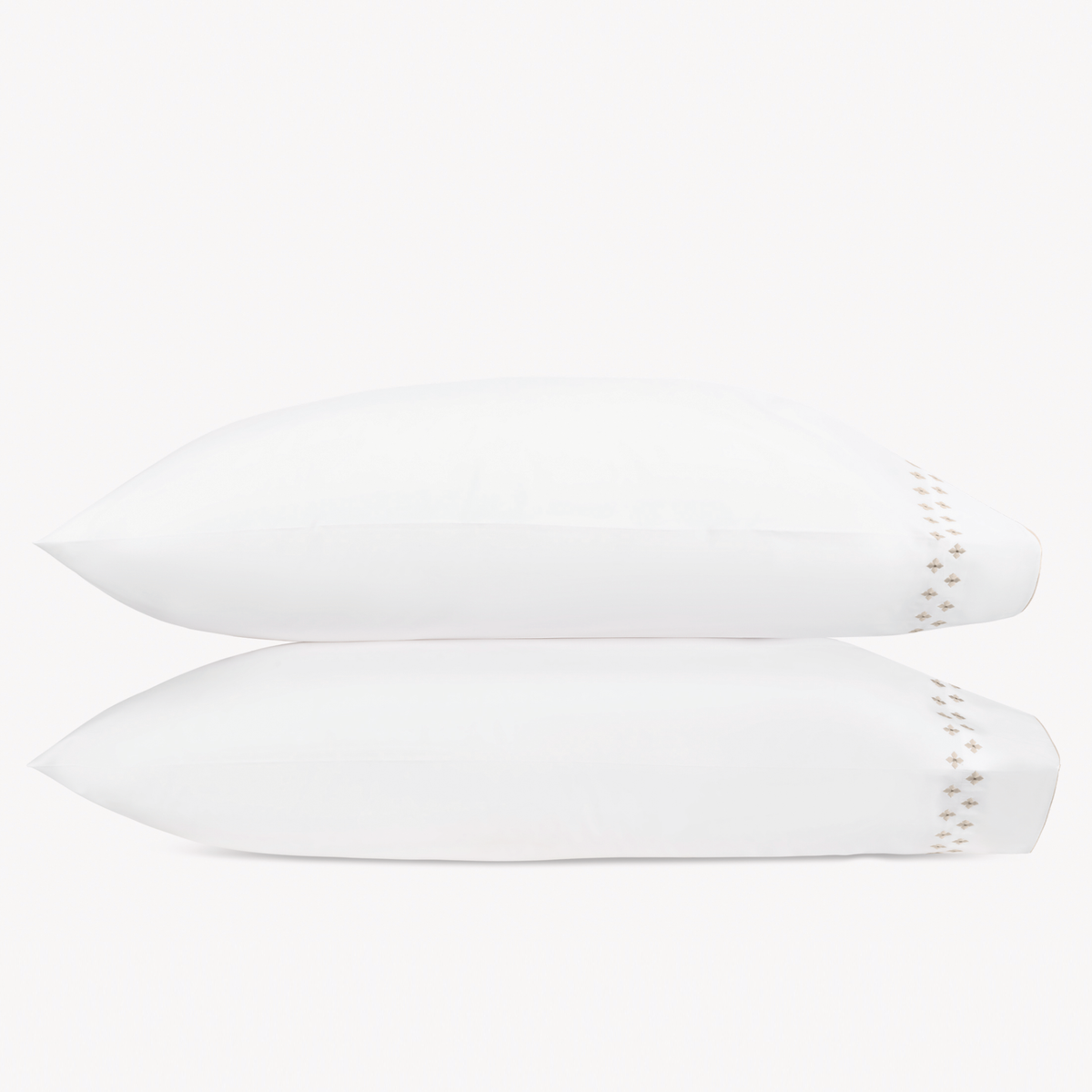 Two white pillows stacked horizontally feature Matouk Casablanca Embroidery in Dune color