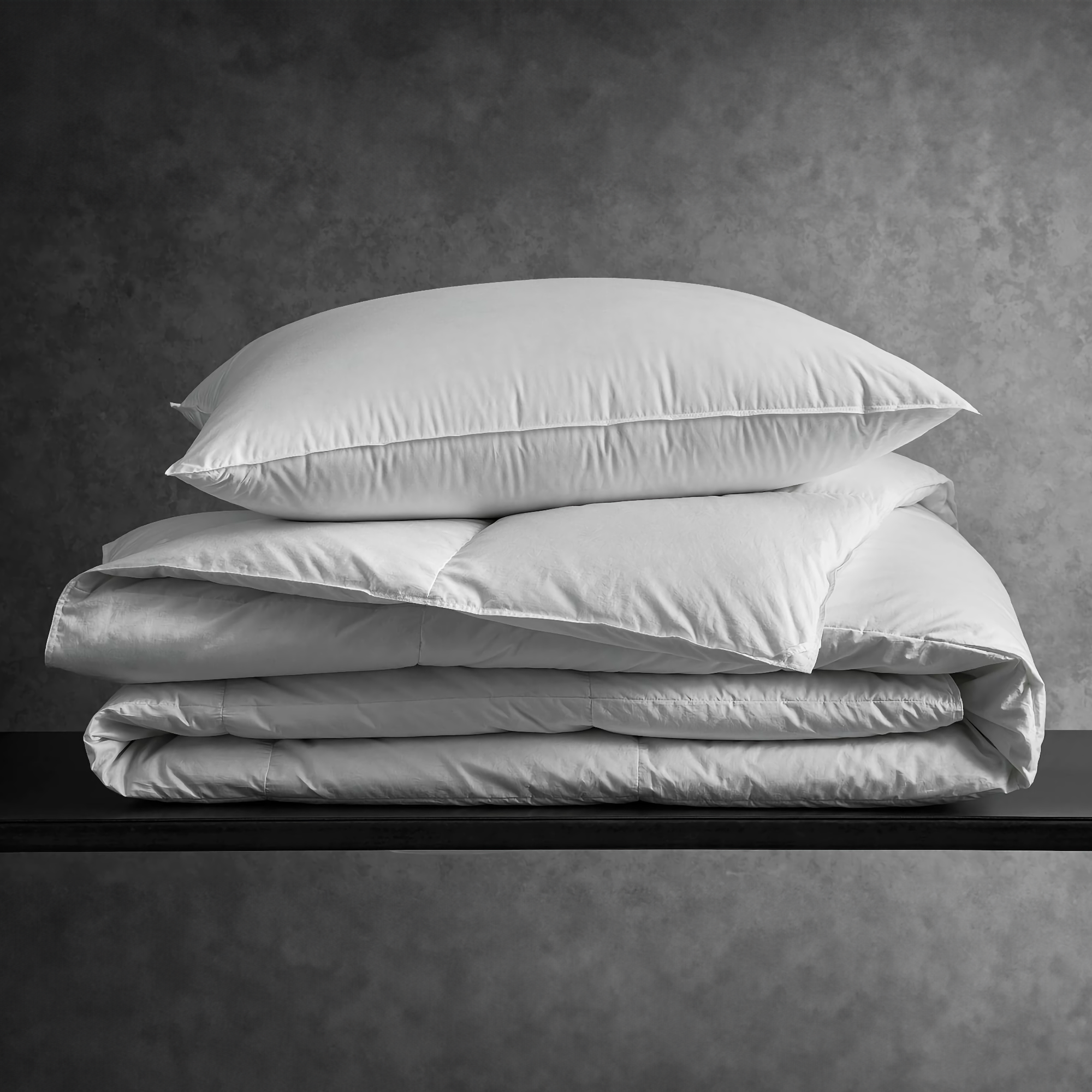 Stack of White Matouk Chalet Comforter and Pillow