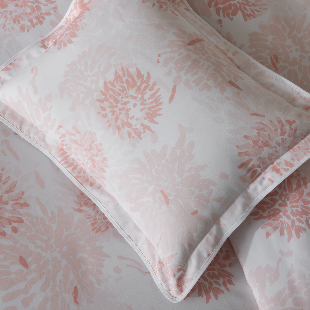 Pillow and bed sheet with a blush floral pattern of Matouk Chrysanthemum collection crafted from Egyptian cotton percale, shown in close-up view