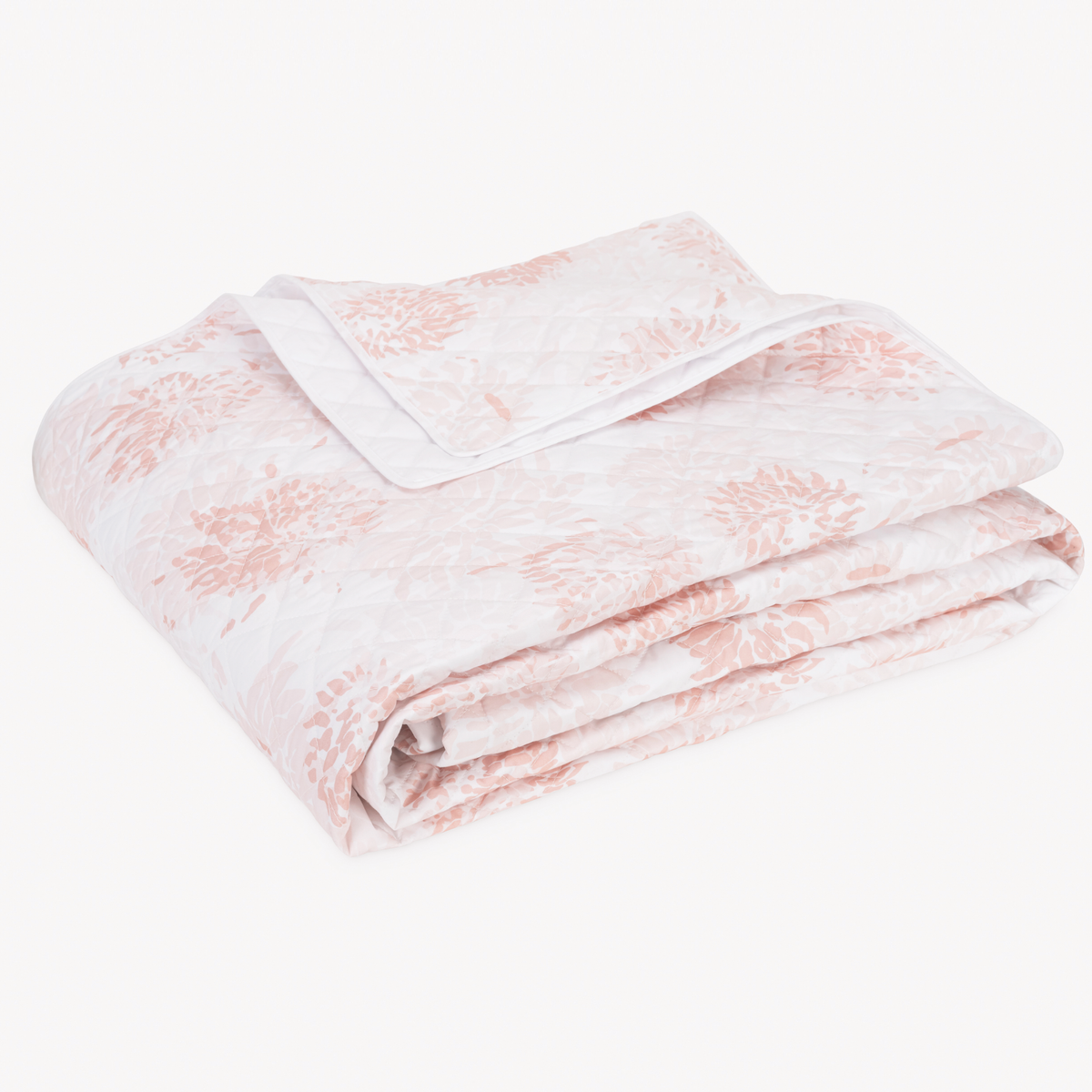 A folded Matouk Chrysanthemum bedding quilt with a blush and white floral pattern