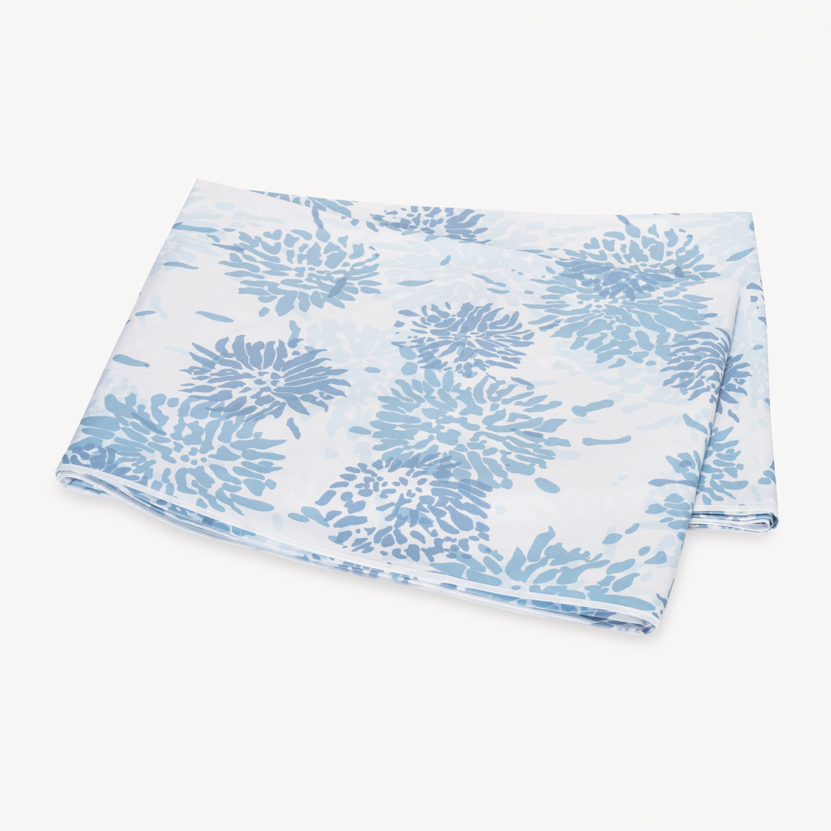 A folded flat sheet with a blue floral pattern from Matouk Chrysanthemum bedding