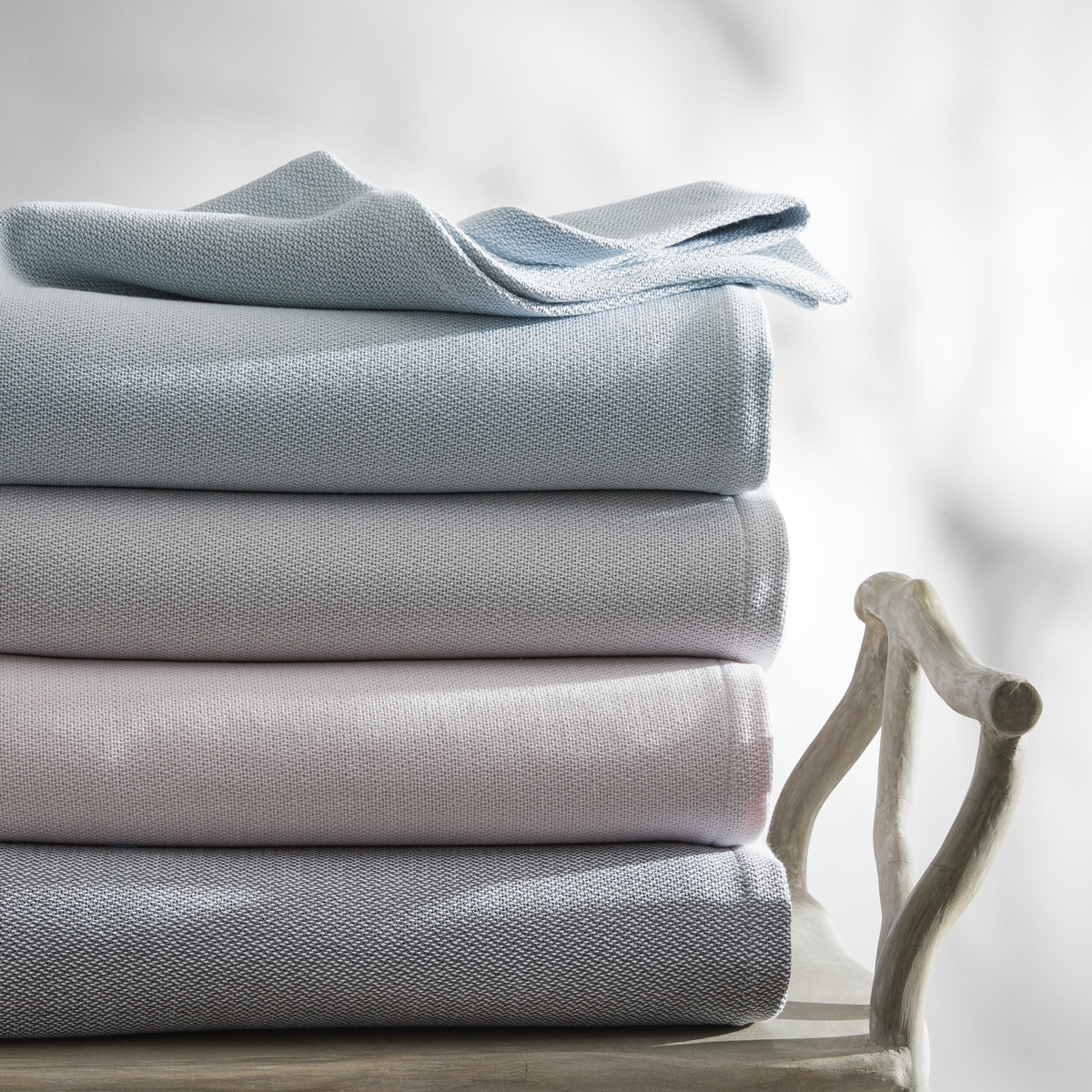 Stack of Matouk Costa Mesa Blankets from top to bottom: Pool, Silver, Pink, and Charcoal
