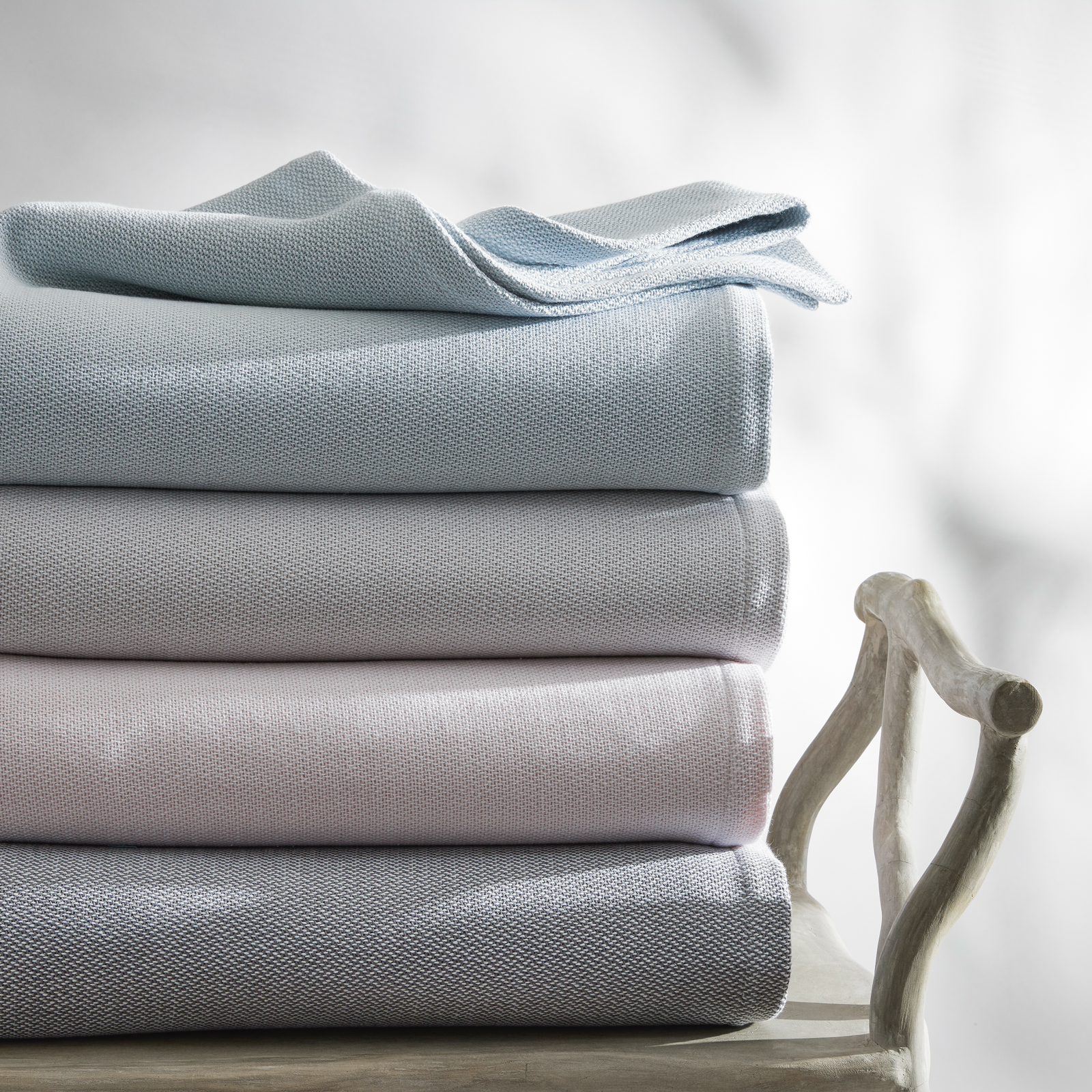 Stack of Matouk Costa Mesa Blankets from top to bottom: Pool, Silver, Pink, and Charcoal
