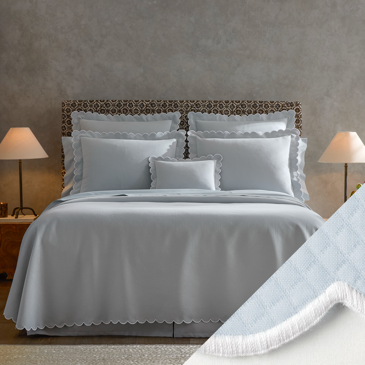 A neatly made bed with Matouk Diamond Pique Bedding, two lamps on nightstands, and a close-up of Light Blue swatch