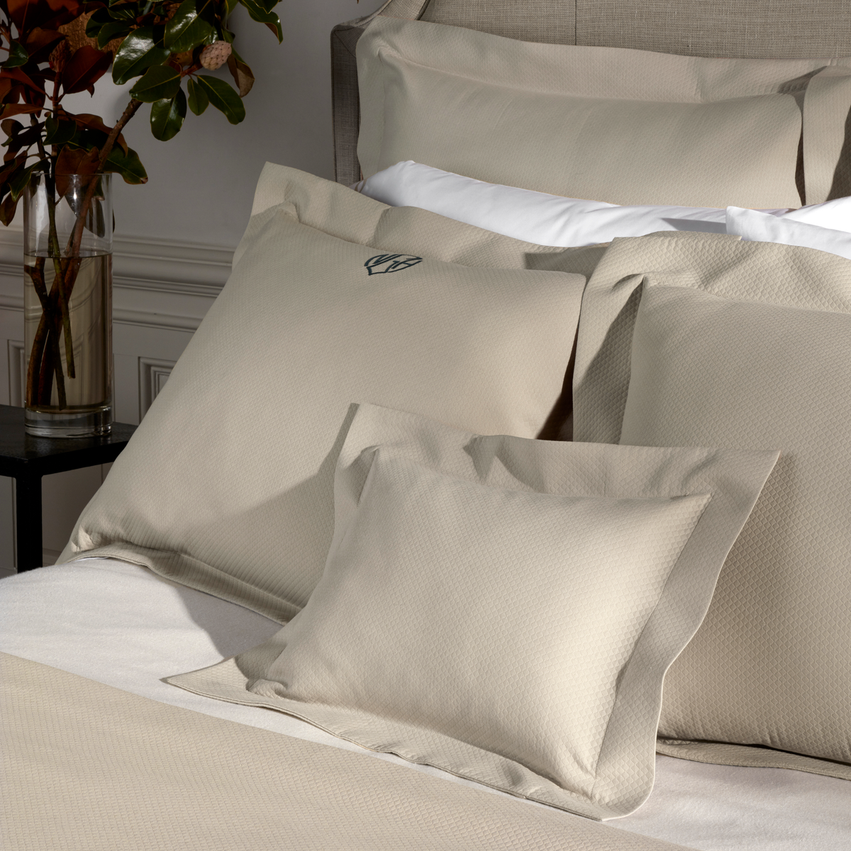 A neatly made bed with Diamond Pique Matouk Elliot Bedding in Dune color