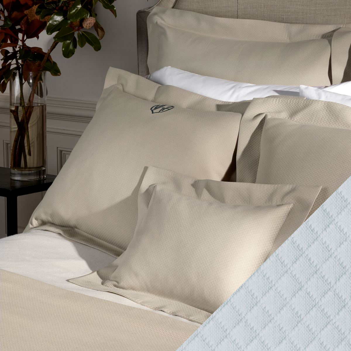 A neatly made bed with Matouk Elliot Bedding and Pool color Diamond Pique Swatch