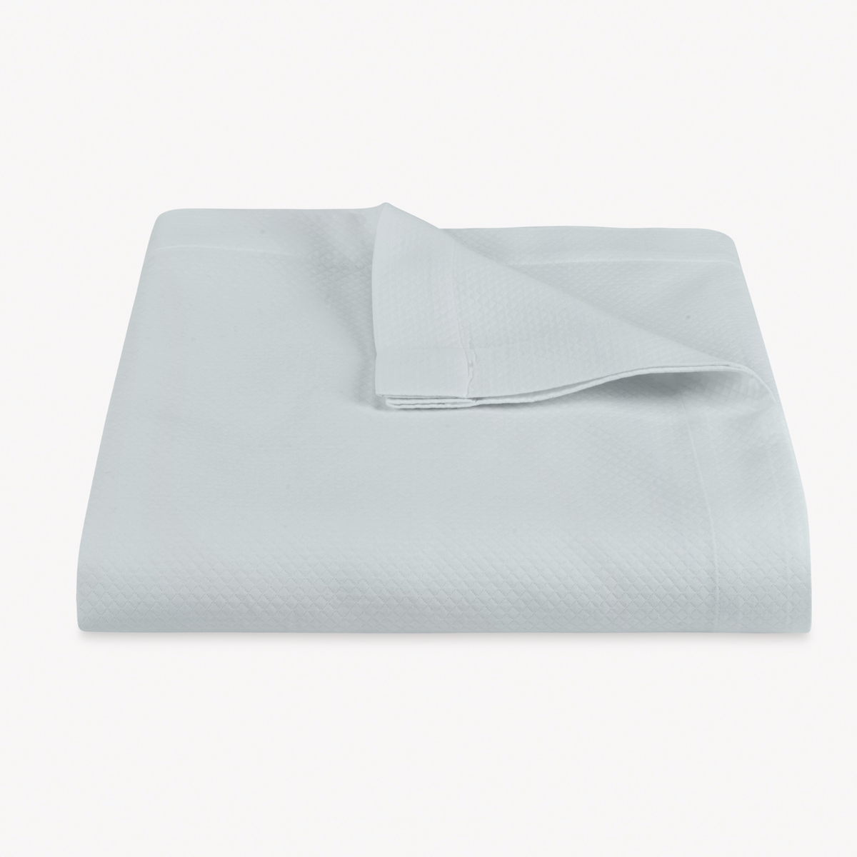 A folded Pool color Matouk Elliot Coverlet with a corner turned down, shown on a plain white background.