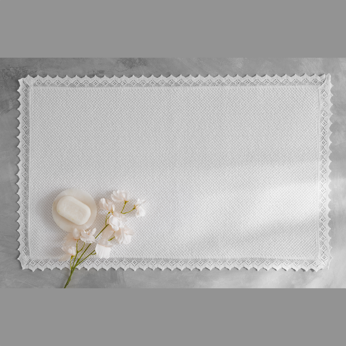White Matouk Ellis Bath Rug with a flower and a soap