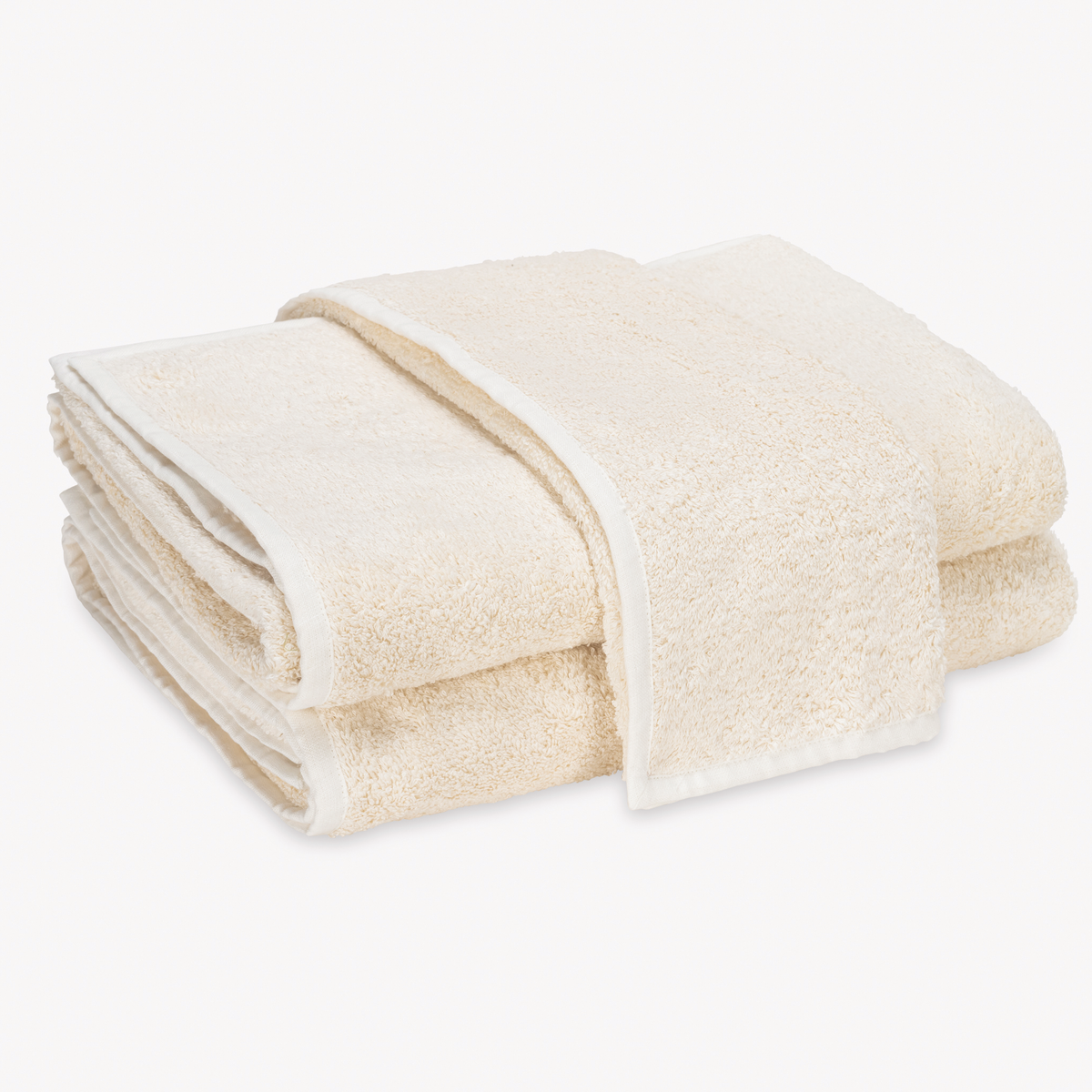 A stack of folded Ivory and Ivory Matouk Enzo Bath Towels on a plain white background.