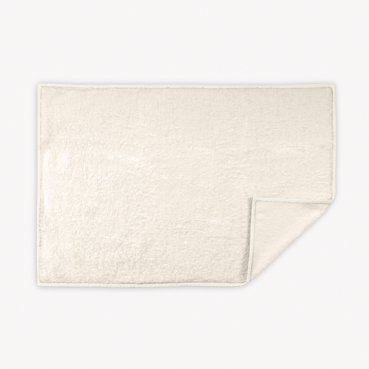 Ivory Ivory Matouk Enzo Tubmat with one corner slightly folded over on a white background