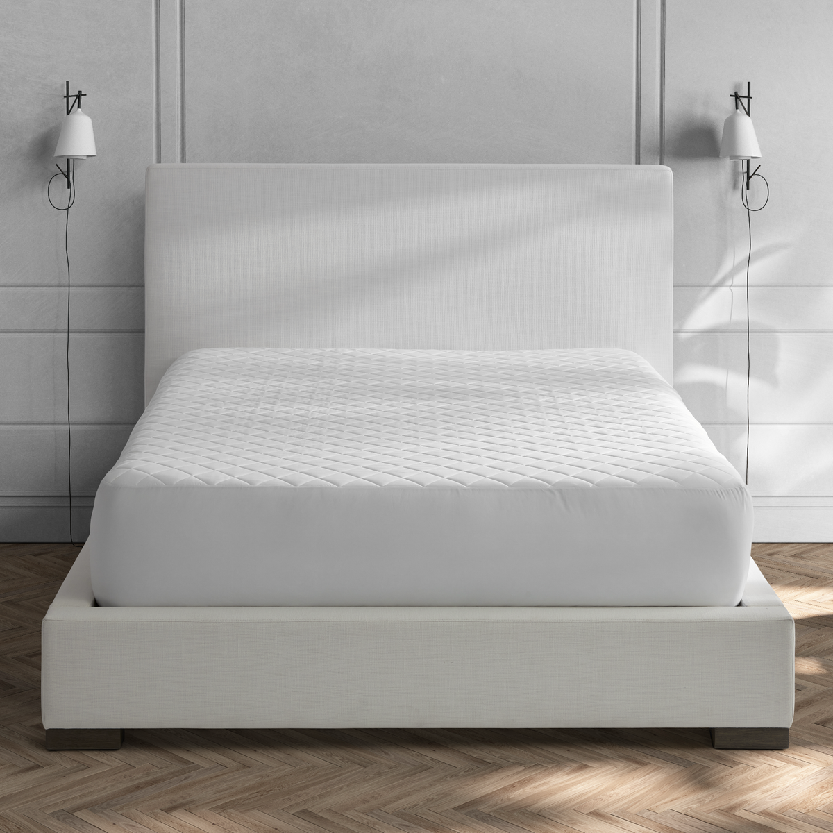 A modern bed with a Matouk Foundation Mattress Pad in a minimalist bedroom with wall-mounted lamps