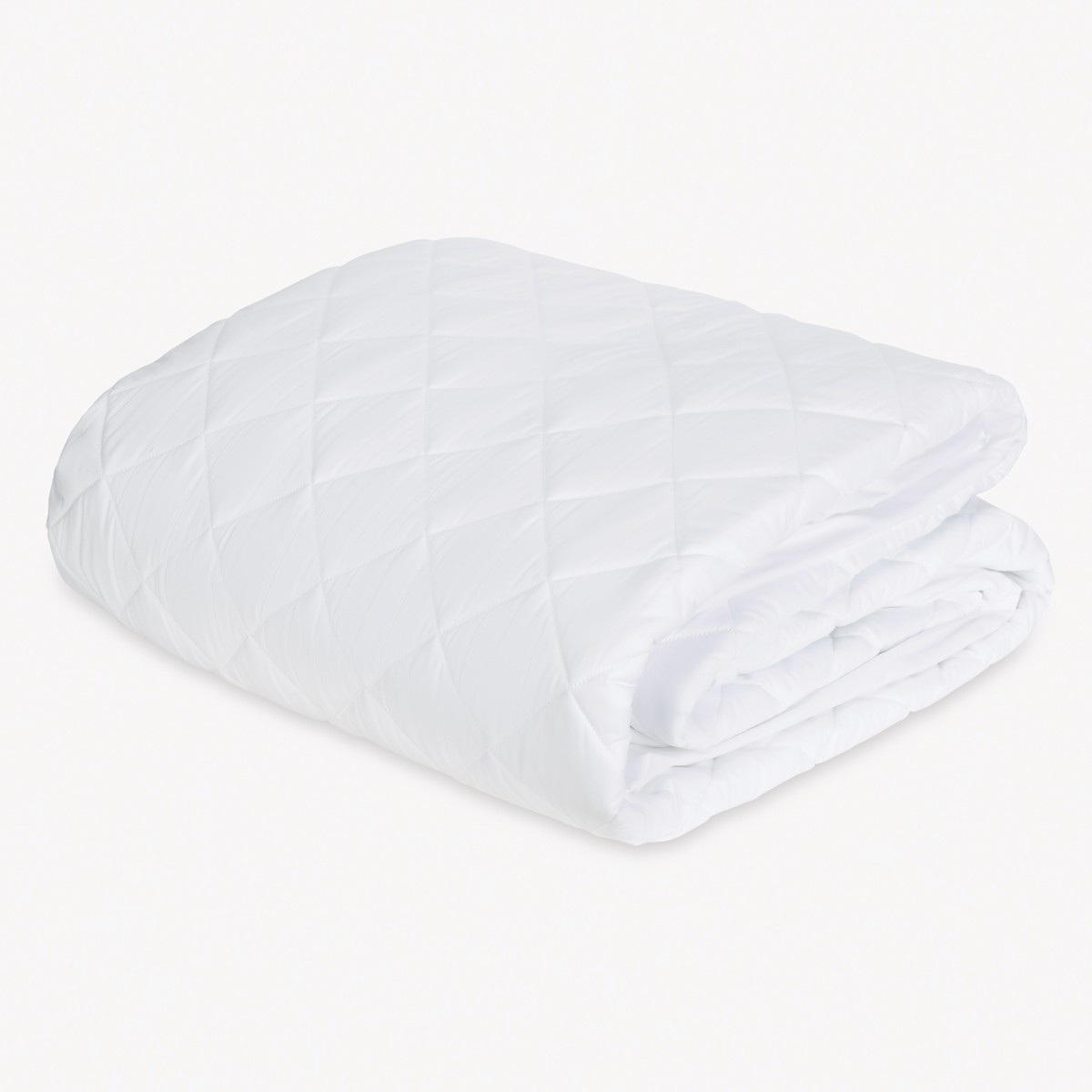 A neatly folded Matouk Foundation Mattress Pad, placed on a plain white background