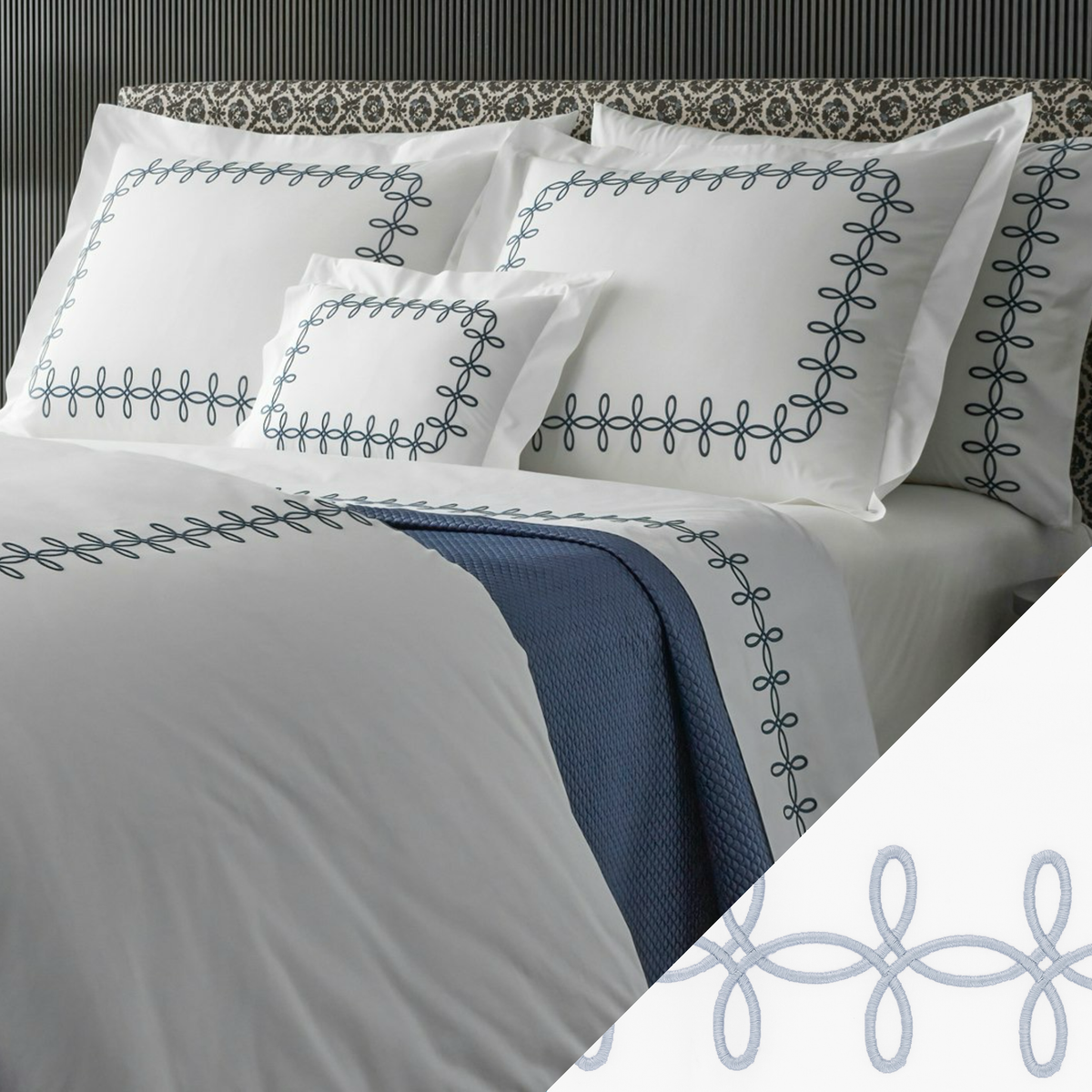A neatly made bed with Matouk Gordian Knot Bedding, Baltic color embroidery, and a Wedgwood swatch