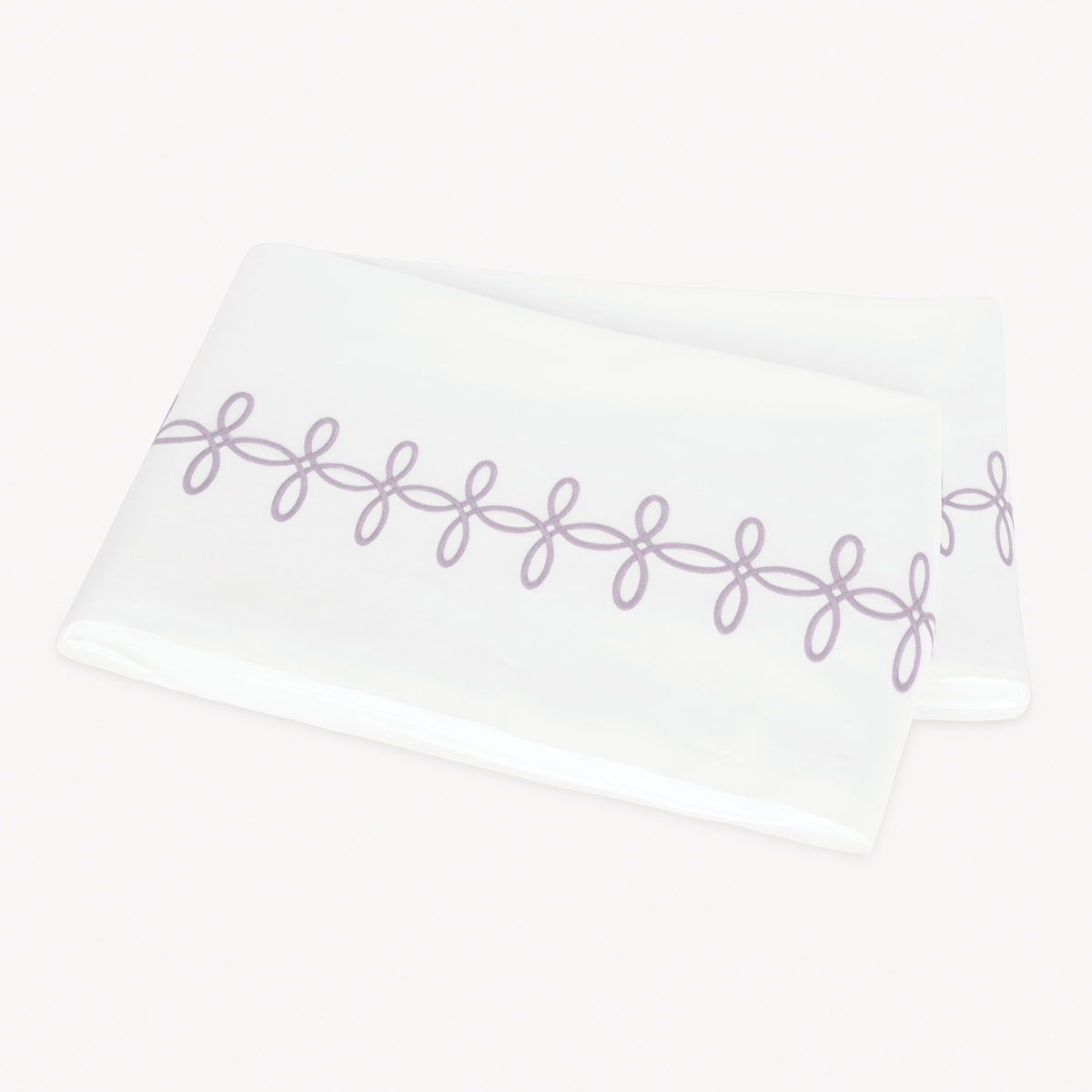 A folded Matouk Gordian Knot Flat Sheet with Lilac color embroidery