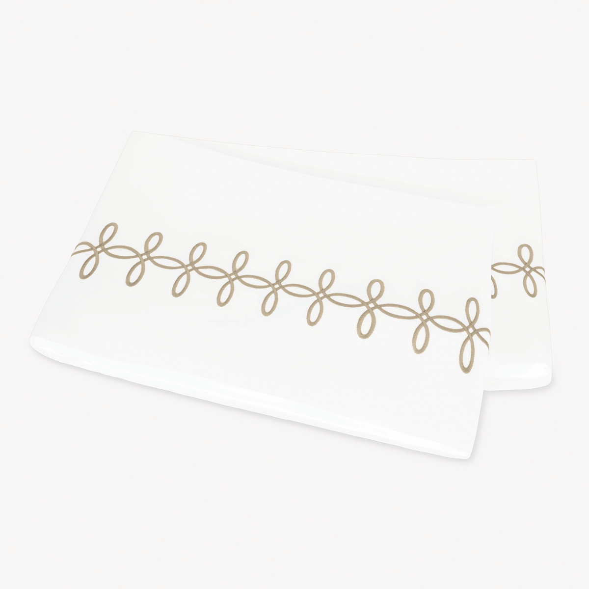 A folded Matouk Gordian Knot Flat Sheet with Truffle color embroidery
