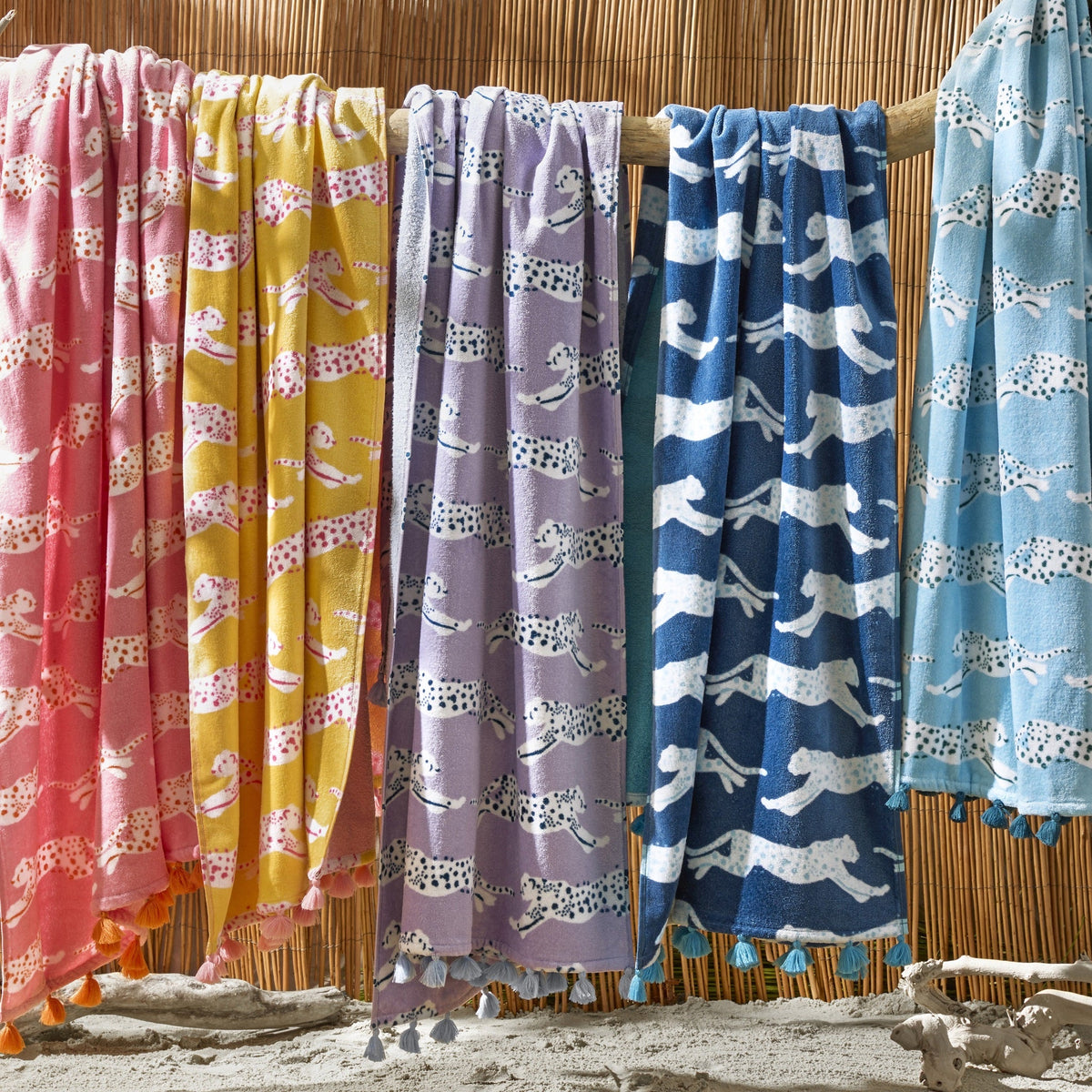 Matouk Leaping Leopard Beach Towels Hanging on a Branch in Different Colors