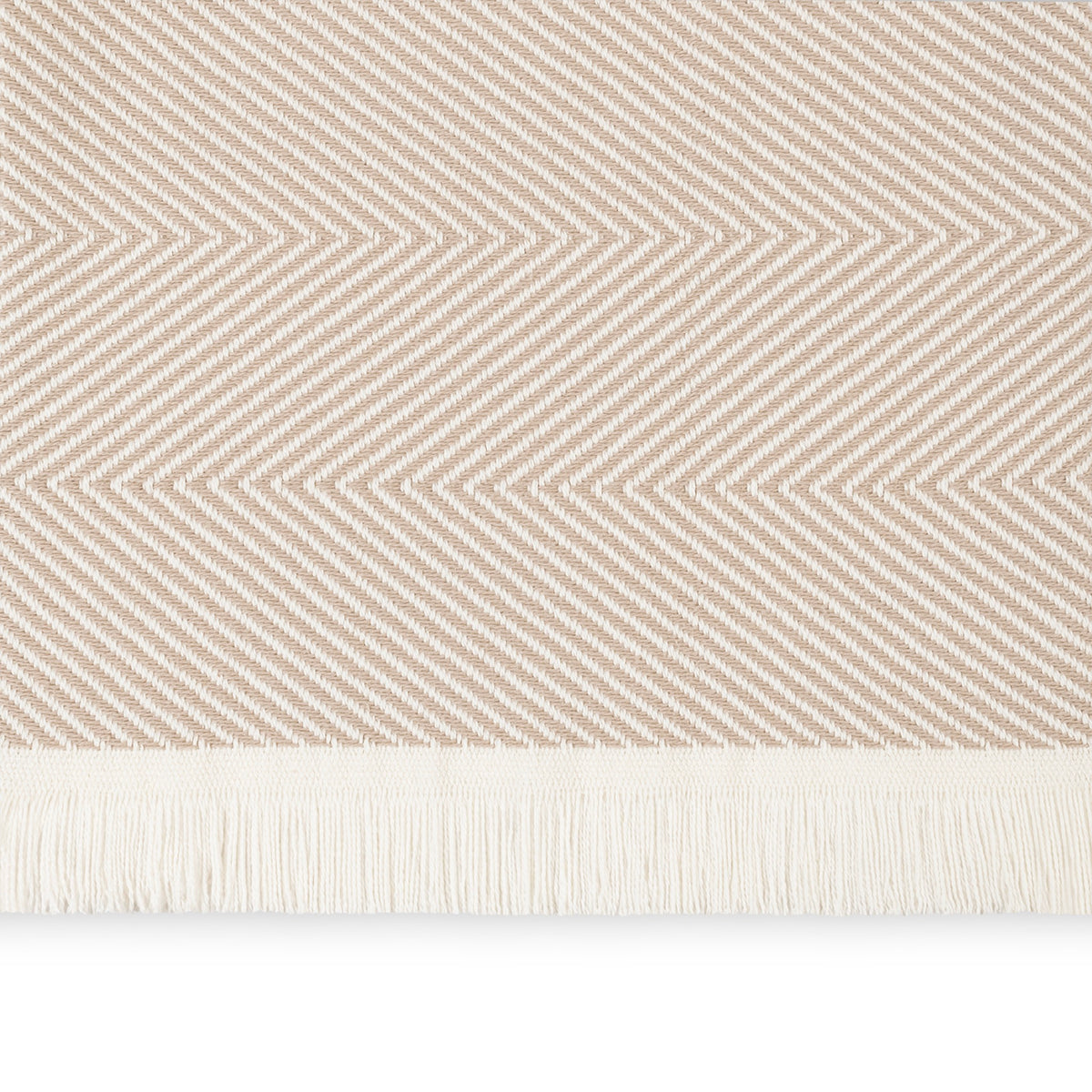 A close-up of a Dune Matouk Leo Throw, a 100% cotton herringbone throw with fringe along the bottom edge