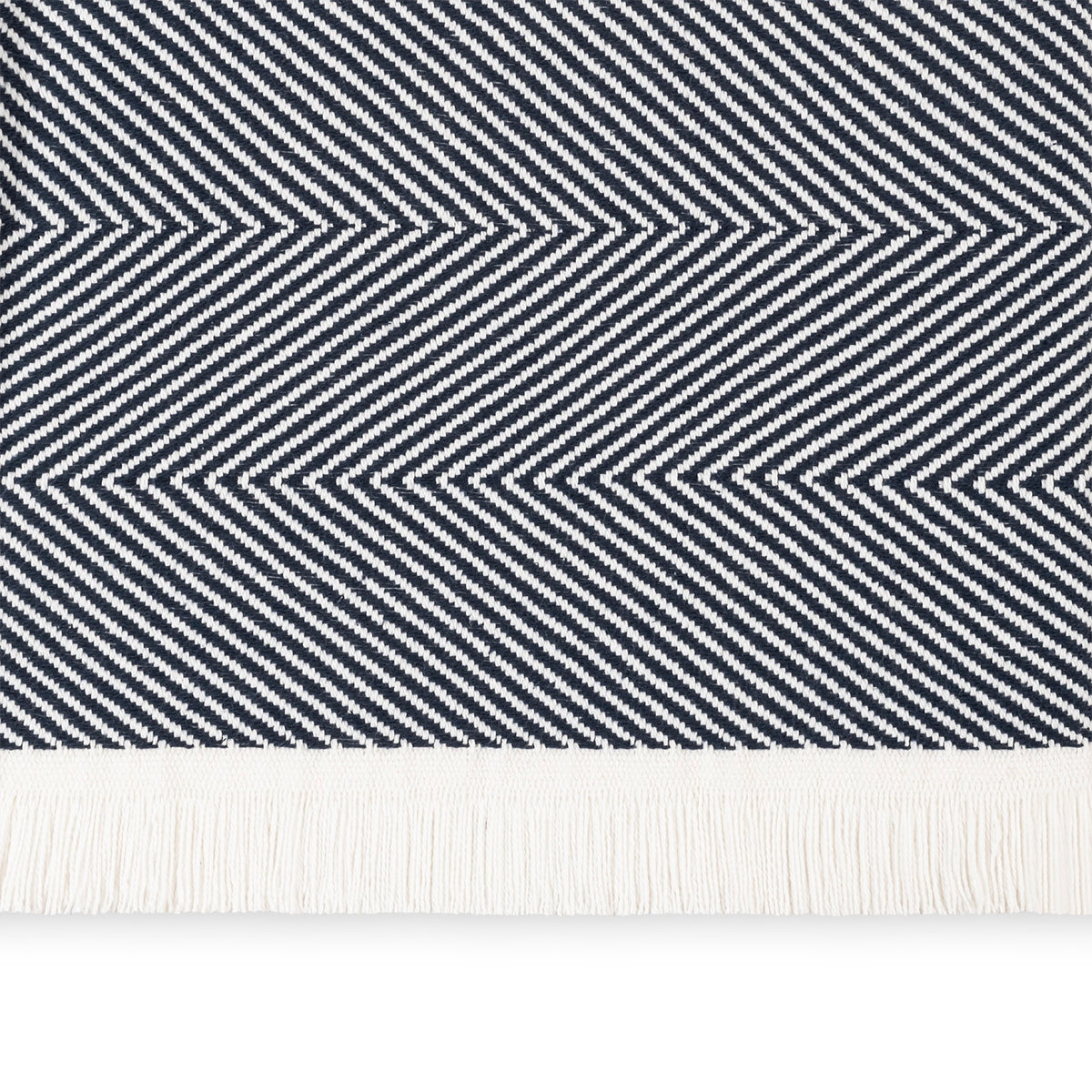 A close-up of a Navy Matouk Leo Throw, a 100% cotton herringbone throw with fringe along the bottom edge