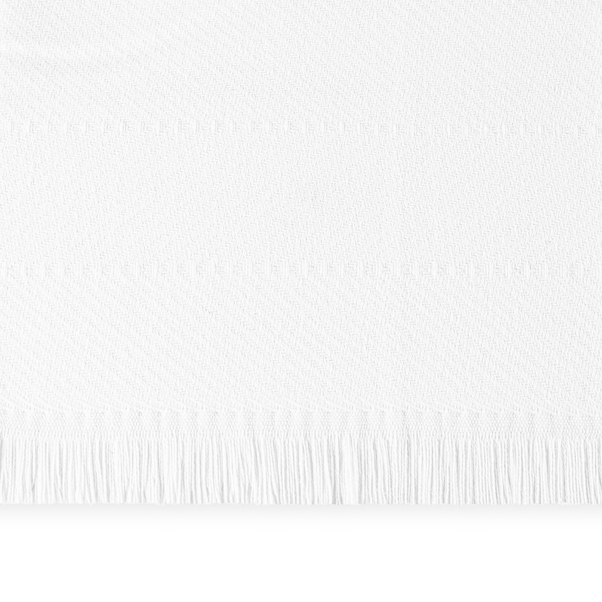 A close-up of a White Matouk Leo Throw, a 100% cotton herringbone throw with fringe along the bottom edge