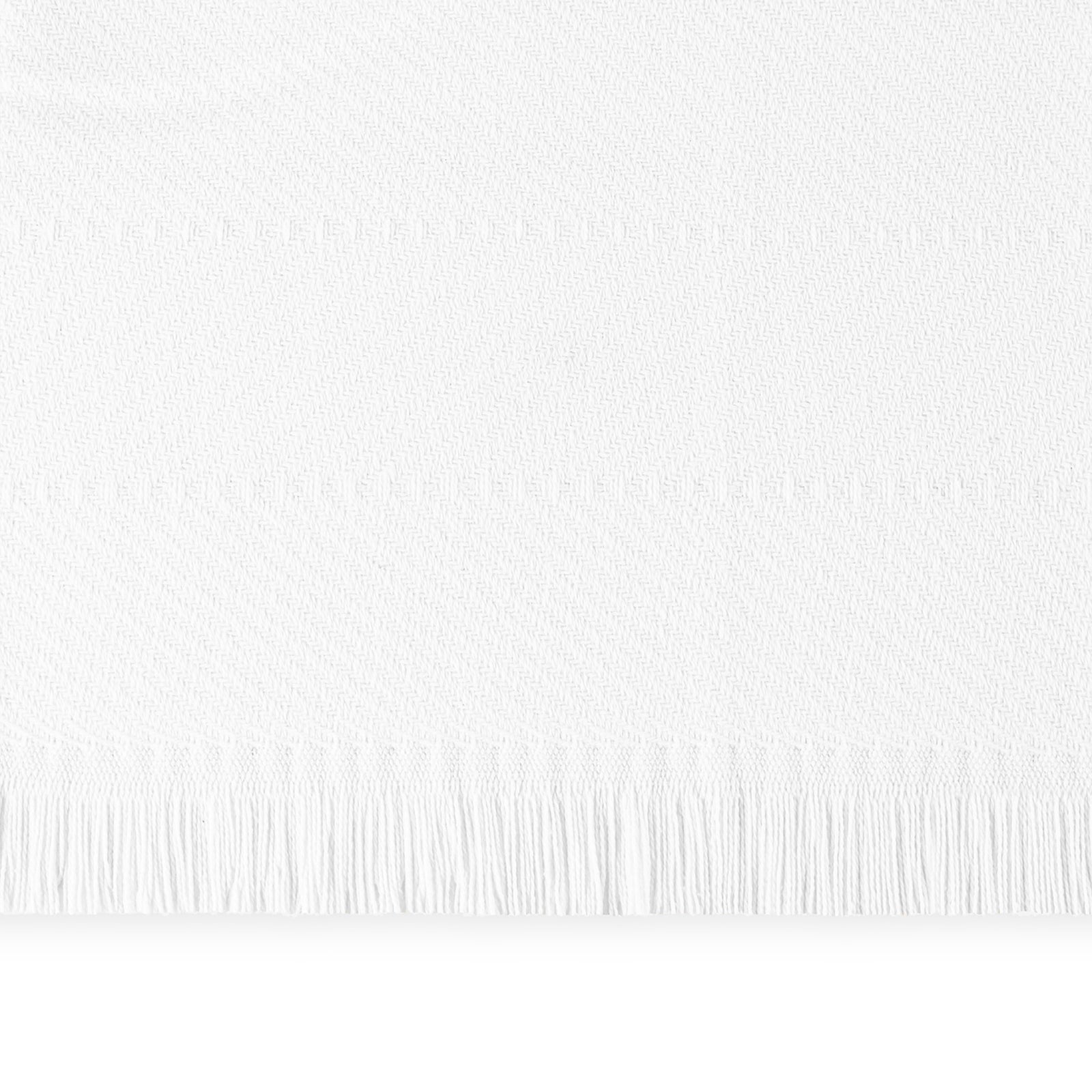 Six folded Matouk Leo herringbone throws in various colors are stacked on a beige cushioned bench.