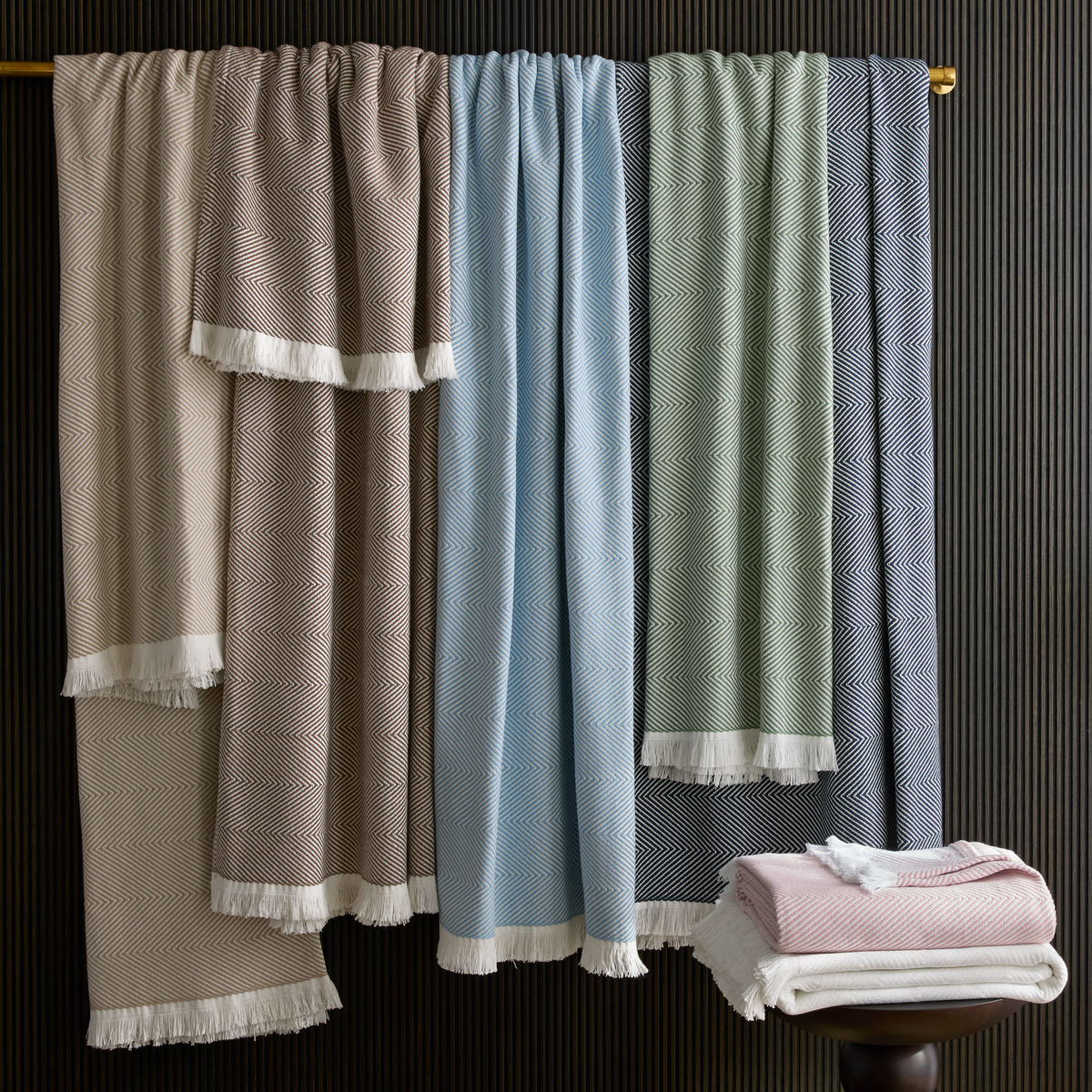 Fringed herringbone Matouk Leo throw blankets hanging on a rod
