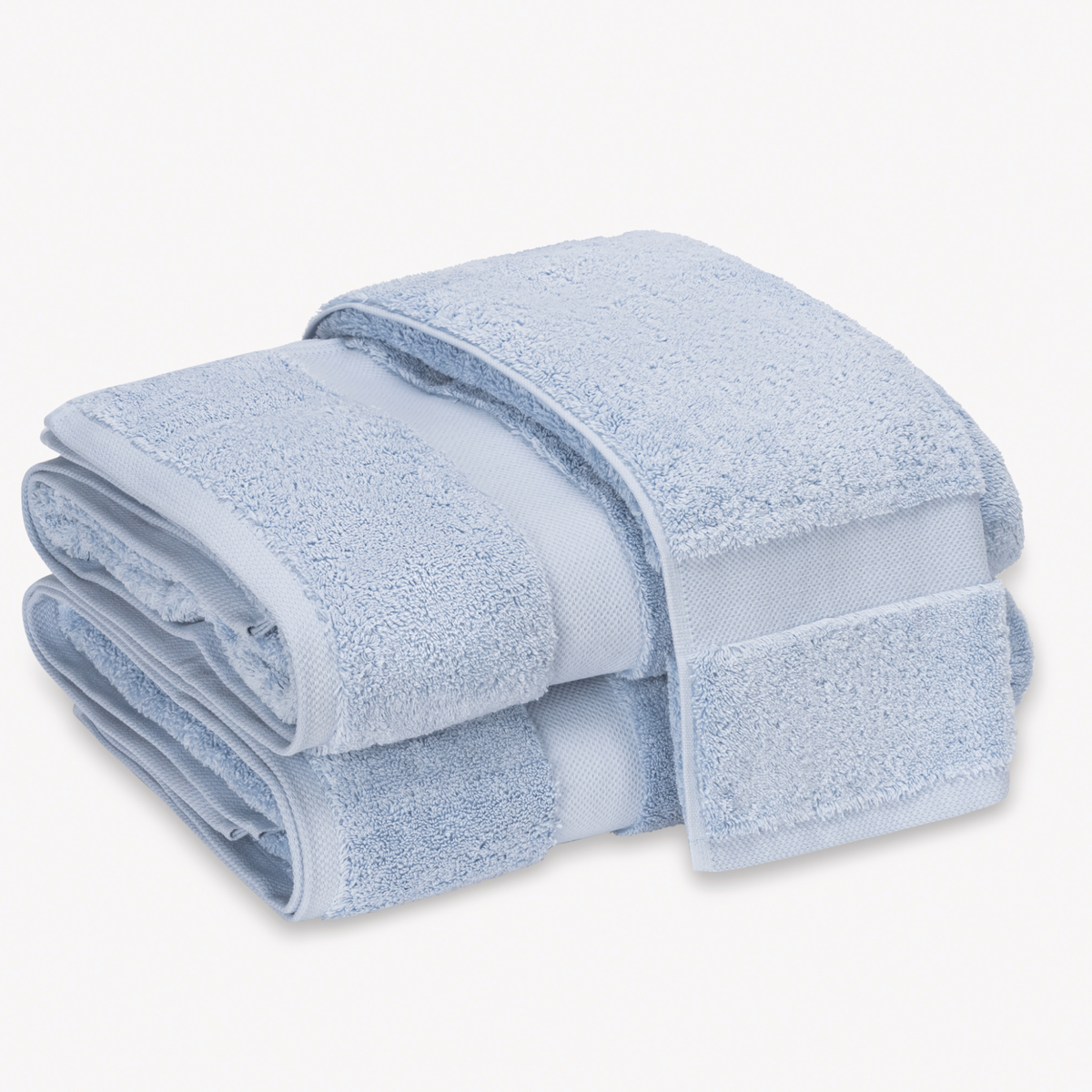 Sky Blue Matouk Lotus Bath Towels 700 GSM stacked on top of each other against a white background