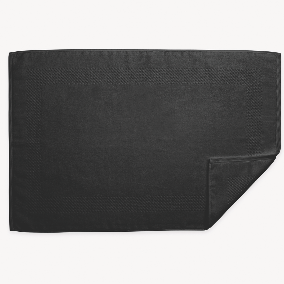 A black rectangular 700 GSM Matouk Lotus Tubmat  and one corner folded over, shown on a white background