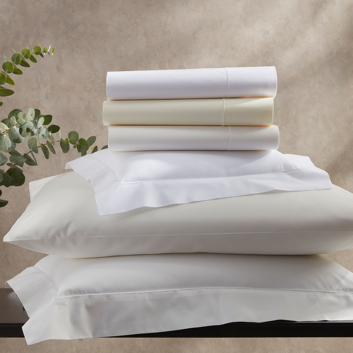 Stack of Matouk Luca Hemstitch Bedding in Assorted Colors