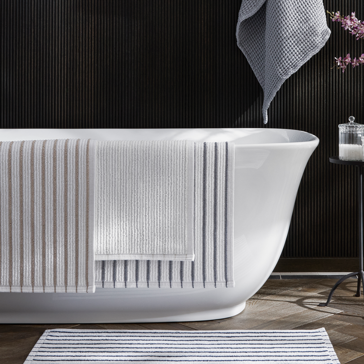 Matouk Marco Bath Rugs in Dove Gray color hanging on a tub