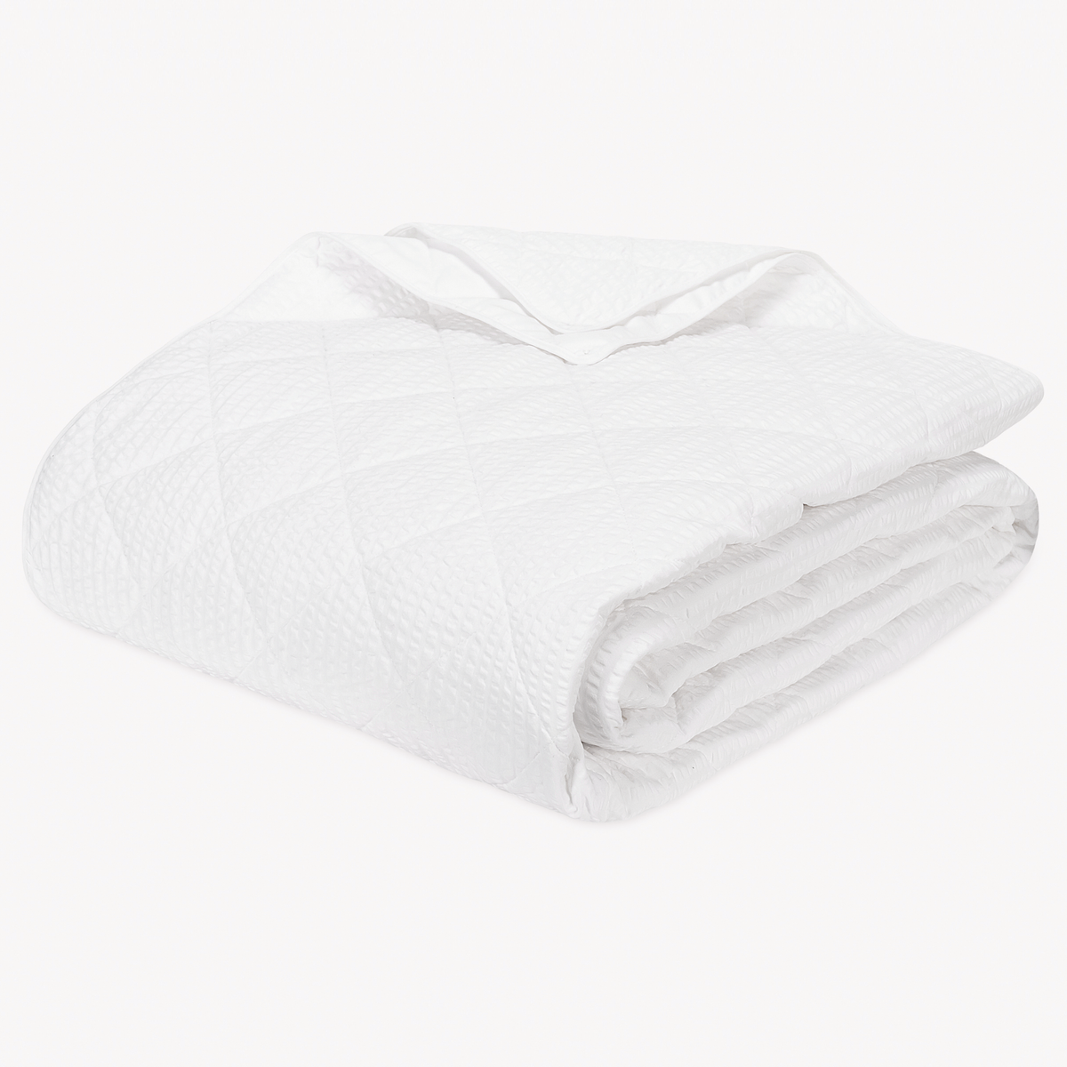 Folded white quilted blanket from the Matouk Matteo Collection, featuring a diamond pattern, on a plain white background.